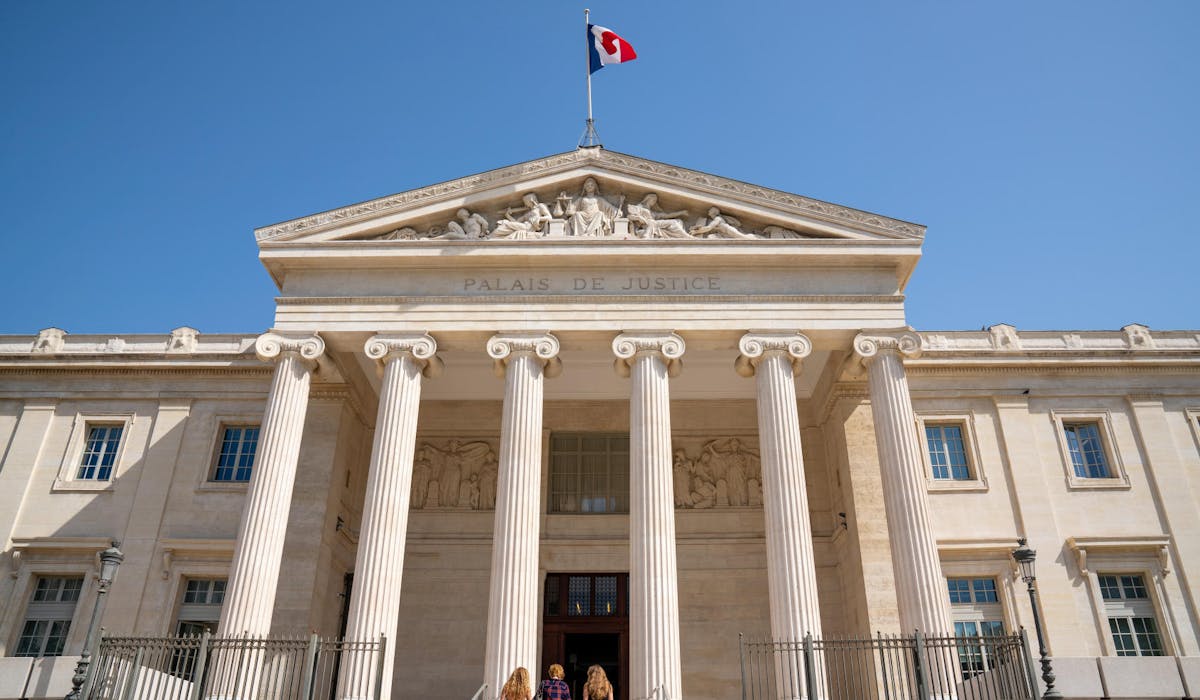 Trois personnes devant un palais de justice