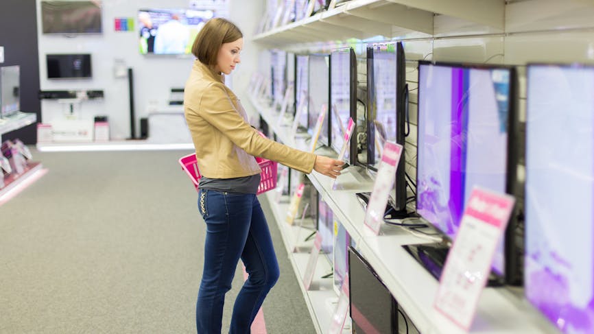 Une cliente regarde les prix des téléviseurs dans un magasin