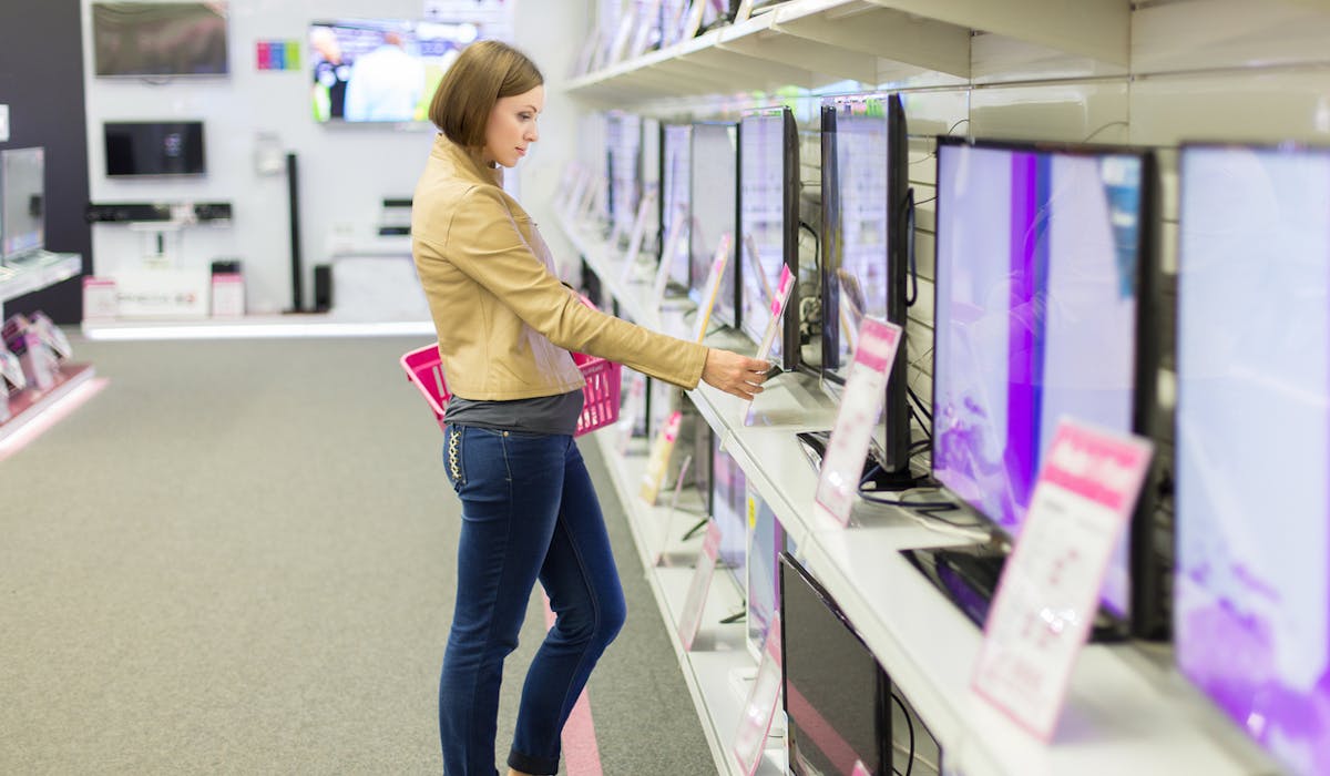 Une cliente regarde les prix des téléviseurs dans un magasin