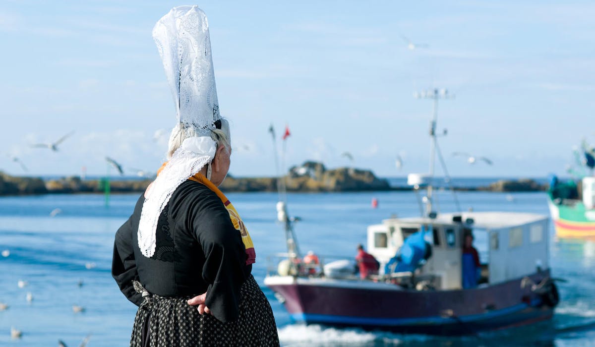 Les marins pêcheurs bretons partent en mer devant une bigoudène