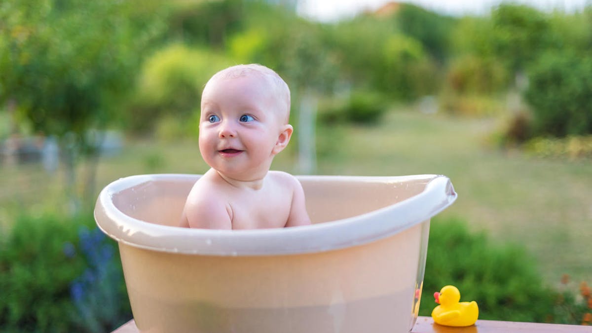 Un bébé est baigné dans une bassine