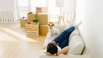Une femme sur son canapé avec son chien dans son nouvel appartement