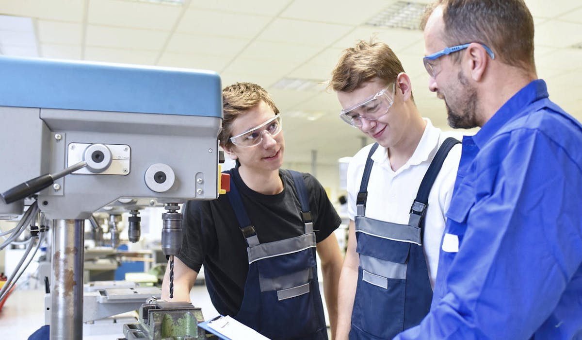 Des jeunes hommes en formation sur une machine industrielle