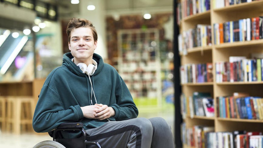 Jeune homme handicapé, fauteuil roulant, bibliothèque