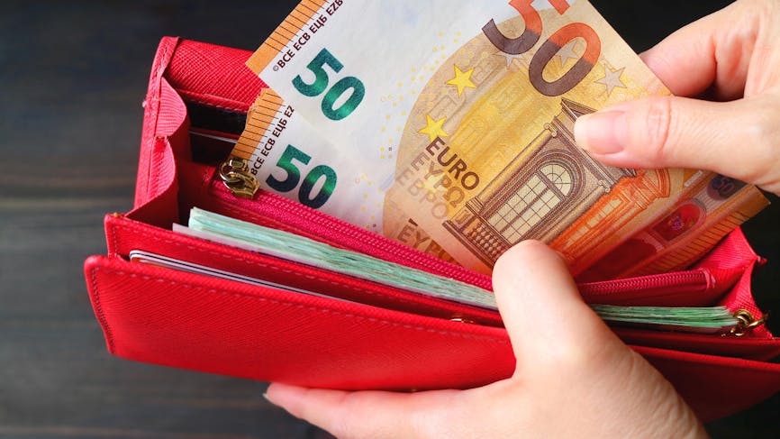 Un portefeuille rouge rempli de billets de 50 et 20 euros