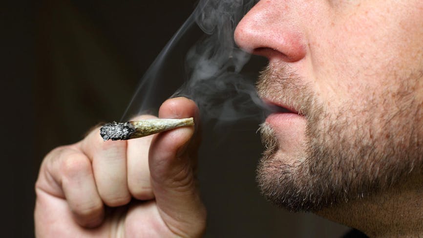 Jeune homme fumant joint de cannabis